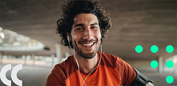 Ein sportlicher junger Mann mit orangefarbenem Laufshirt und Kopfhörern lächelt fröhlich. Auf einem grünen Störer rechts neben ihm steht "Aktion bis 31.05.2025".